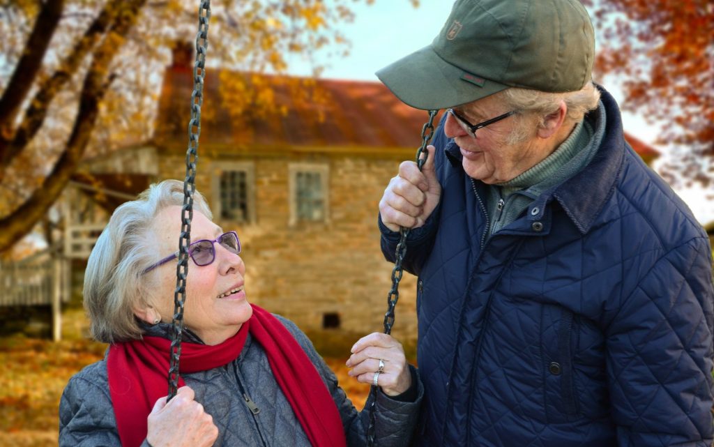 Pflegekraft spricht mit einer Seniorin im Garten